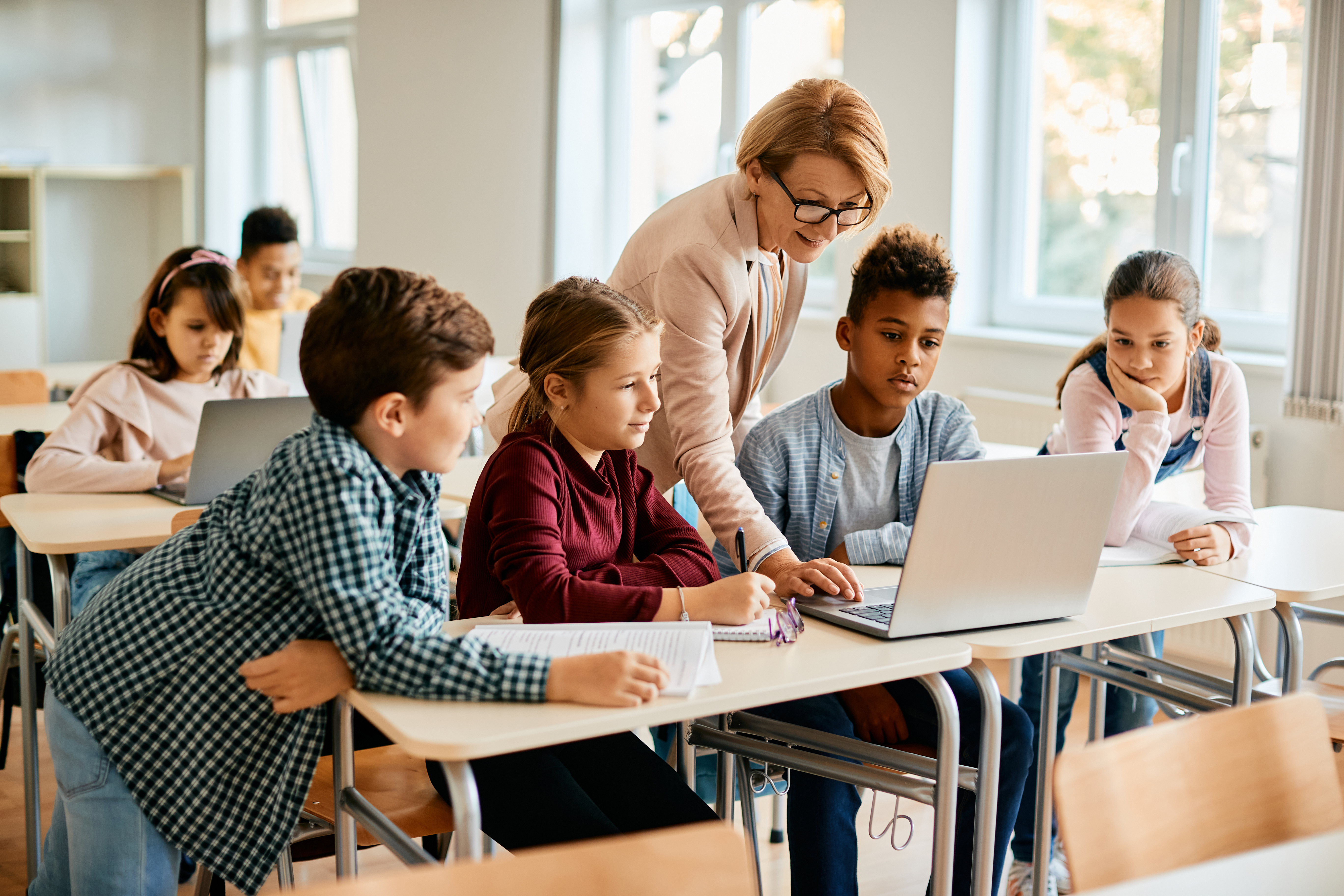 school teacher helping kids at computer